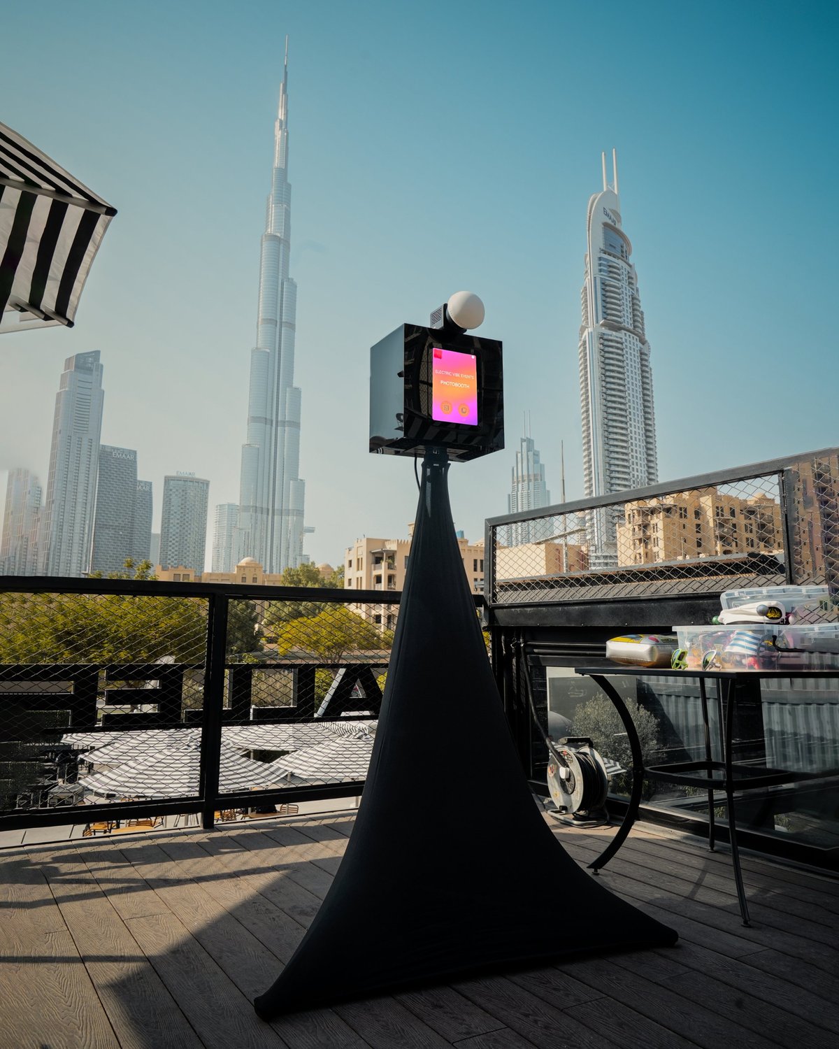 Black Electric Vibe photo booth on a rooftop terrace in Downtown Dubai with the Burj Khalifa behind it